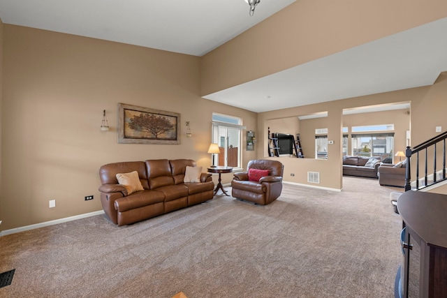 carpeted living area with baseboards, stairs, and visible vents