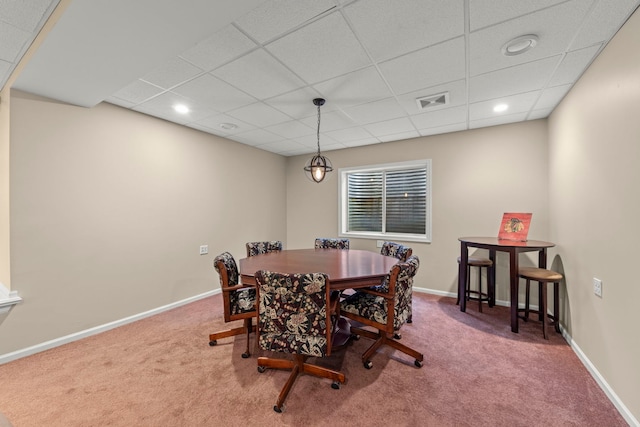 carpeted dining room with visible vents, baseboards, and a drop ceiling