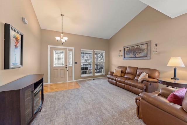 carpeted living area with high vaulted ceiling, a notable chandelier, and baseboards