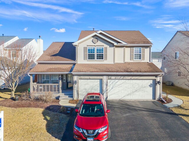 traditional home featuring a garage, covered porch, driveway, and a shingled roof