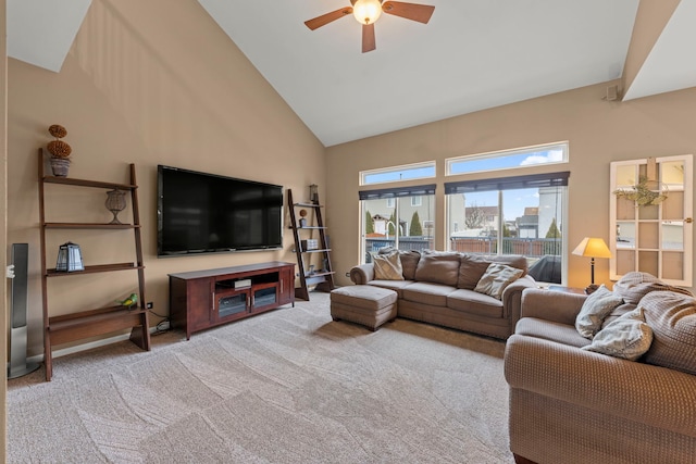 carpeted living area with ceiling fan and high vaulted ceiling