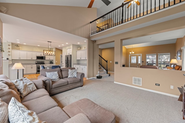 living room with light carpet, baseboards, visible vents, stairway, and a high ceiling