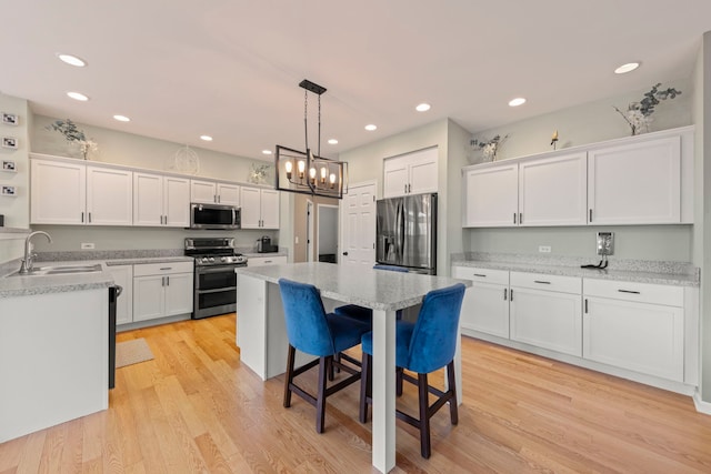 kitchen with a kitchen island, white cabinetry, stainless steel appliances, and a sink