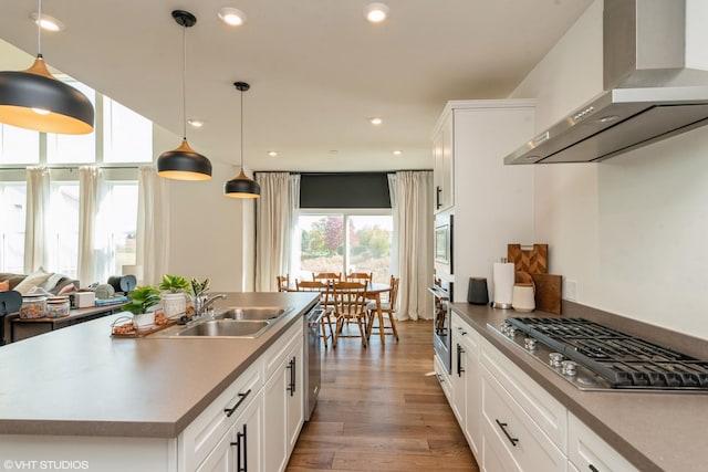 kitchen featuring recessed lighting, a sink, light wood-style floors, appliances with stainless steel finishes, and wall chimney exhaust hood