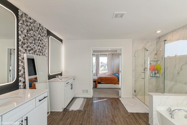 bathroom with a marble finish shower, a sink, visible vents, wood tiled floor, and connected bathroom