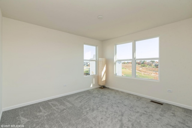 unfurnished room featuring carpet, visible vents, and baseboards