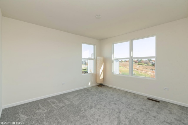 empty room with baseboards, visible vents, and carpet