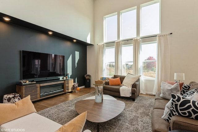 living room featuring a towering ceiling, baseboards, and wood finished floors