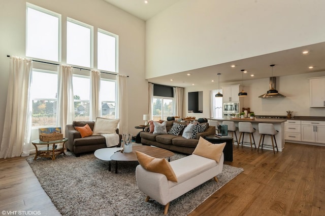 living room featuring a towering ceiling, light wood-style floors, and recessed lighting