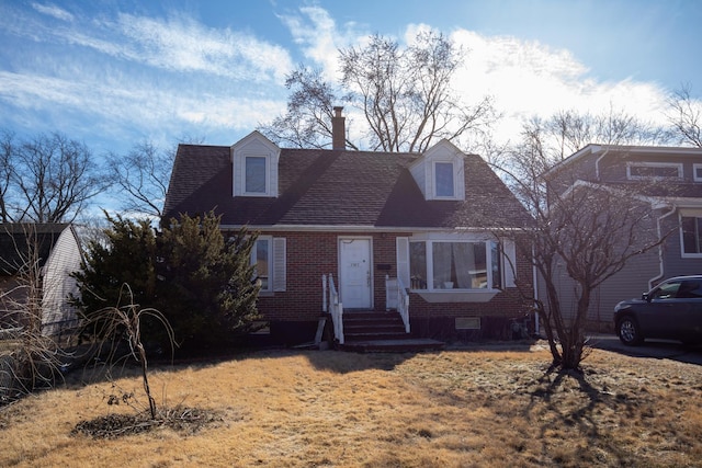 cape cod house featuring roof with shingles and brick siding