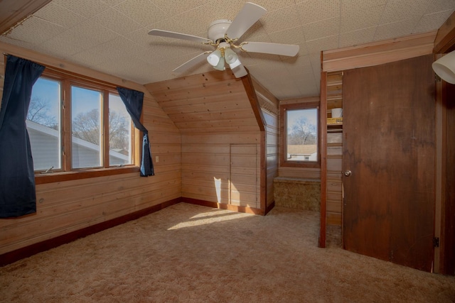 additional living space featuring carpet floors, lofted ceiling, ceiling fan, and wooden walls