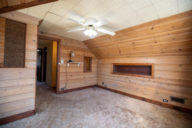 bonus room featuring visible vents, a ceiling fan, carpet flooring, vaulted ceiling, and wood walls