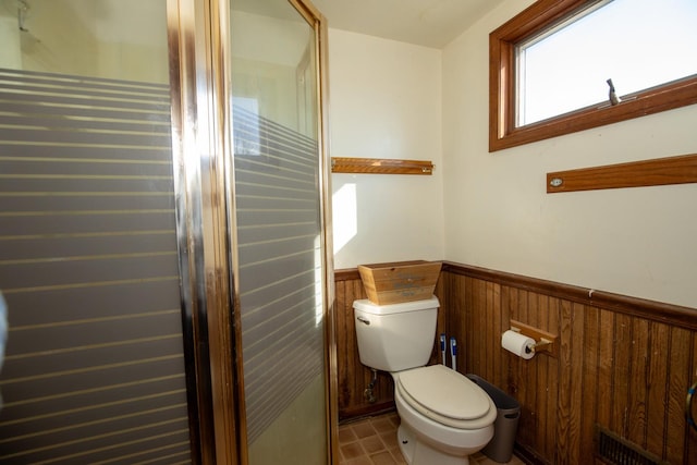 bathroom featuring toilet, wooden walls, visible vents, and wainscoting