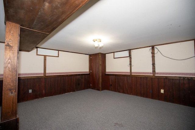 carpeted spare room featuring wood walls and wainscoting