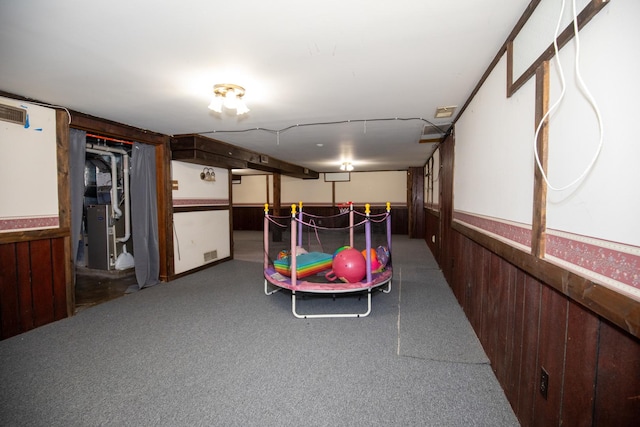 interior space featuring visible vents, a wainscoted wall, wooden walls, and heating unit