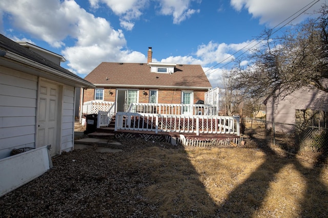 rear view of property featuring a shingled roof, brick siding, fence, and a wooden deck