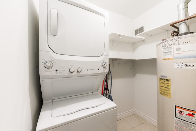 washroom featuring visible vents, water heater, stacked washing maching and dryer, light tile patterned flooring, and laundry area