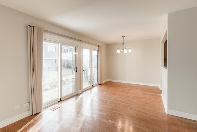 unfurnished room featuring a chandelier, visible vents, light wood-style flooring, and baseboards