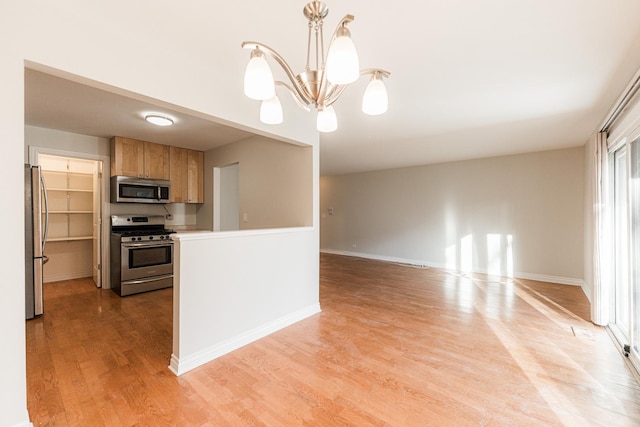 kitchen featuring baseboards, a chandelier, light countertops, light wood-style flooring, and appliances with stainless steel finishes