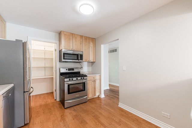 kitchen featuring light wood-type flooring, visible vents, light brown cabinets, stainless steel appliances, and light countertops