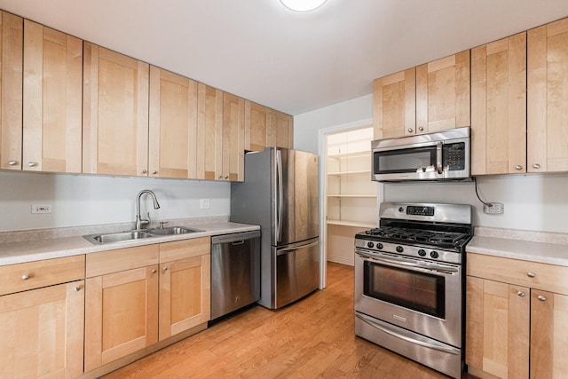 kitchen featuring light wood finished floors, light brown cabinetry, a sink, appliances with stainless steel finishes, and light countertops