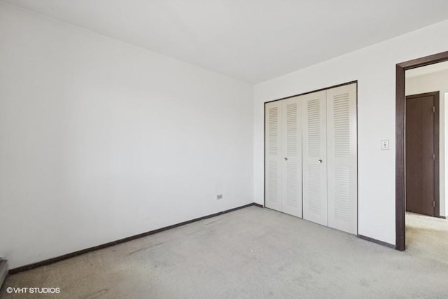 unfurnished bedroom with a closet, light colored carpet, and baseboards