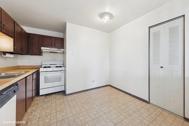 kitchen with light floors, light countertops, dark brown cabinetry, white appliances, and under cabinet range hood