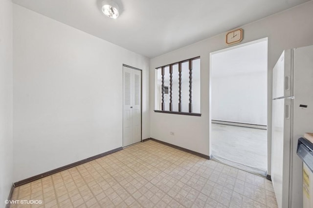 empty room featuring light floors, a baseboard radiator, and baseboards