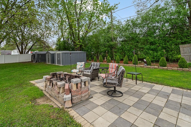 view of patio featuring an outdoor fire pit, a shed, and an outbuilding