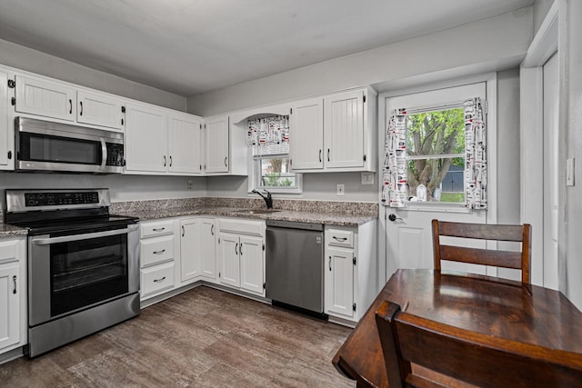 kitchen featuring stainless steel appliances, a sink, dark wood-style floors, and white cabinetry