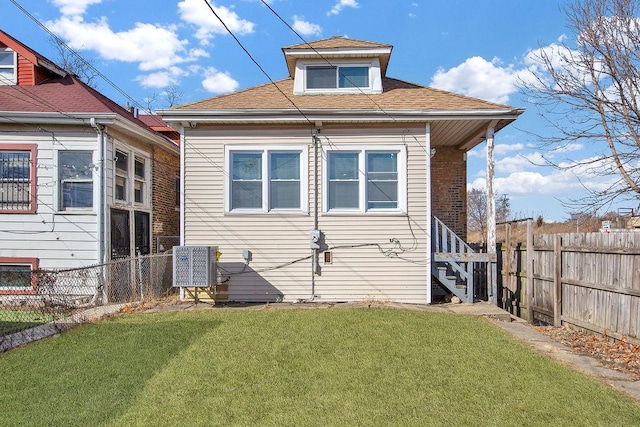 rear view of property featuring central air condition unit, roof with shingles, a yard, and fence