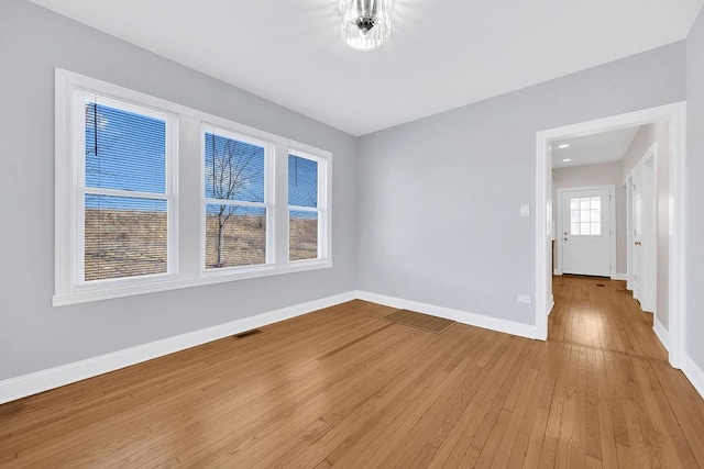 empty room with visible vents, light wood-style flooring, and baseboards