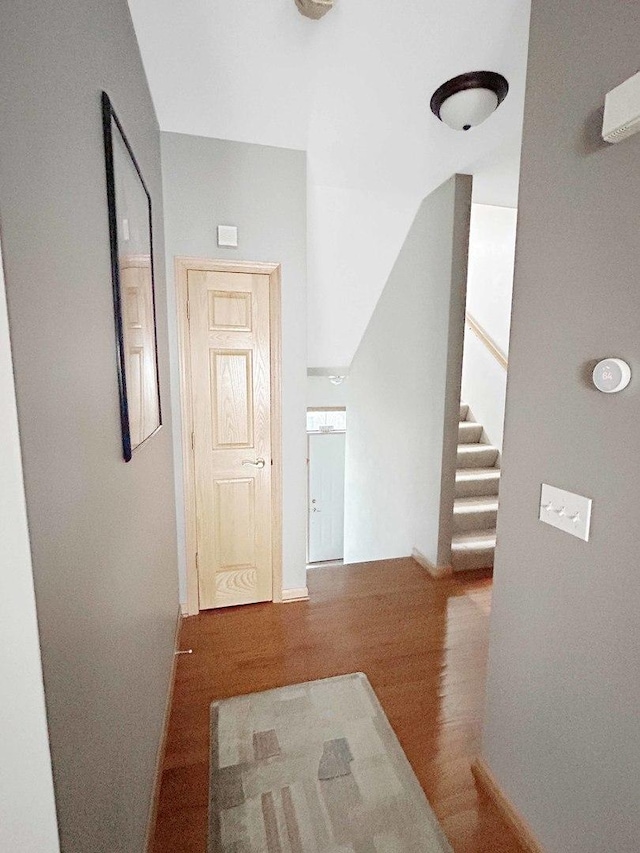 hall featuring stairway, wood finished floors, and baseboards