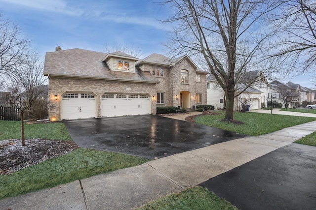 view of front of property with driveway, a chimney, an attached garage, a front lawn, and brick siding