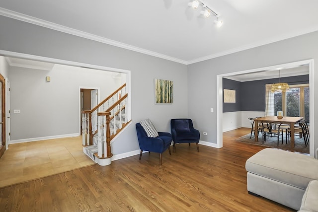 living area featuring crown molding, stairs, baseboards, and wood finished floors