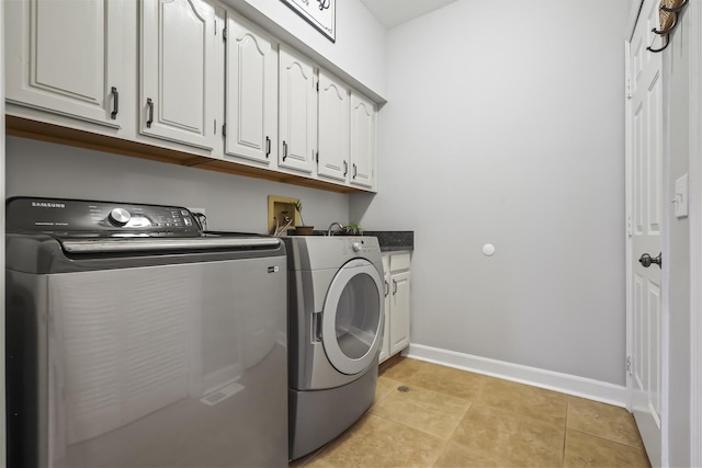 clothes washing area with washer and dryer, cabinet space, baseboards, and light tile patterned floors