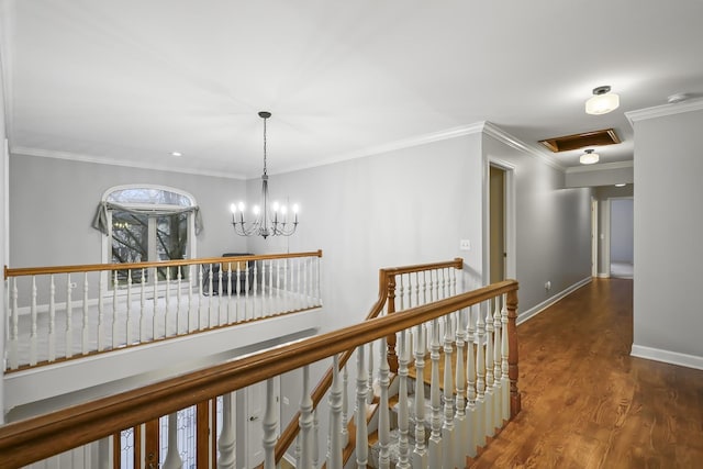 hallway with wood finished floors, an upstairs landing, baseboards, an inviting chandelier, and crown molding