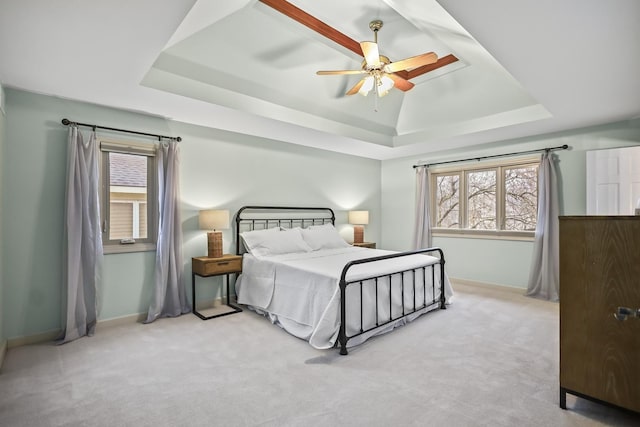 carpeted bedroom with a tray ceiling, ceiling fan, and baseboards