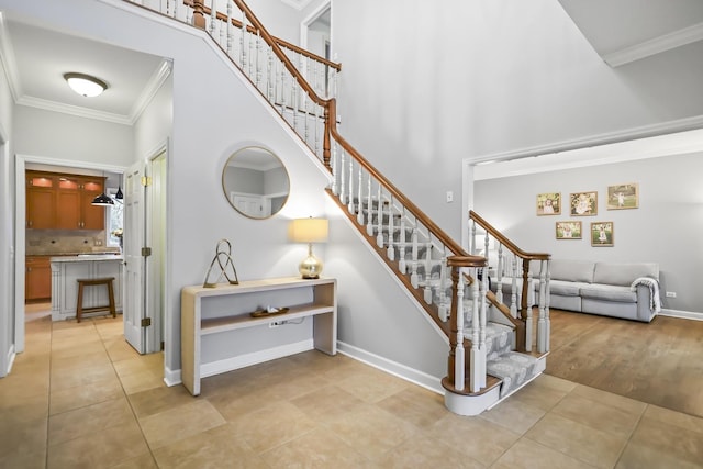 stairs with baseboards, a high ceiling, ornamental molding, and tile patterned floors