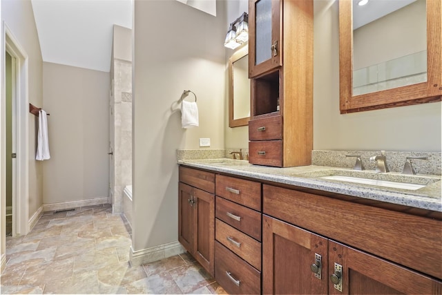 full bathroom featuring double vanity, stone finish flooring, a sink, baseboards, and a bath