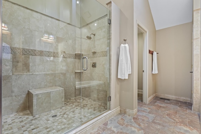 full bathroom with stone finish flooring, a shower stall, and baseboards