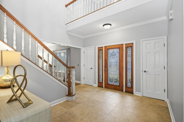 tiled entryway featuring stairs, ornamental molding, a high ceiling, and baseboards