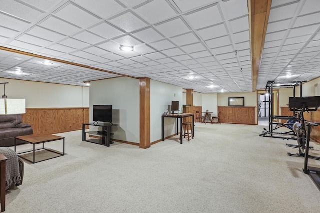 living room with a wainscoted wall, wood walls, and a paneled ceiling