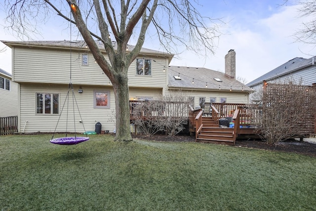 rear view of house with a yard, a chimney, and a wooden deck