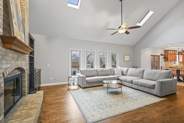 living room featuring a skylight, a fireplace, dark wood-style floors, and high vaulted ceiling