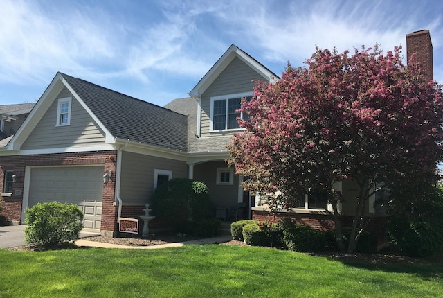 view of front of property featuring brick siding, concrete driveway, a front lawn, and roof with shingles