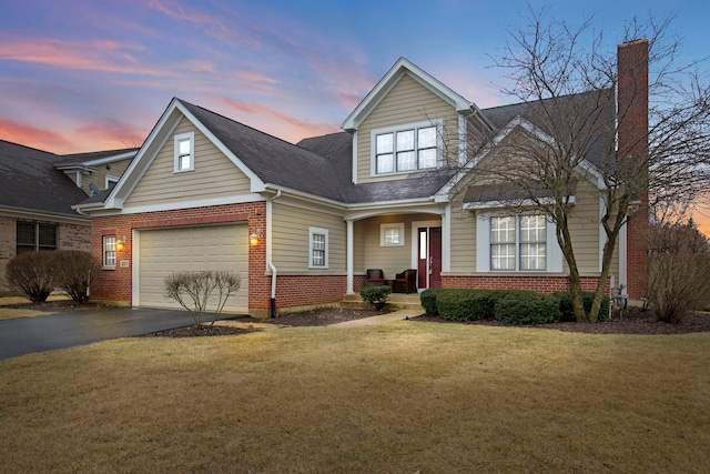 view of front of property featuring roof with shingles, driveway, a chimney, a front lawn, and brick siding