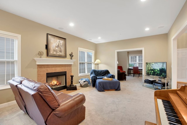 living area featuring a tiled fireplace, recessed lighting, baseboards, and light carpet