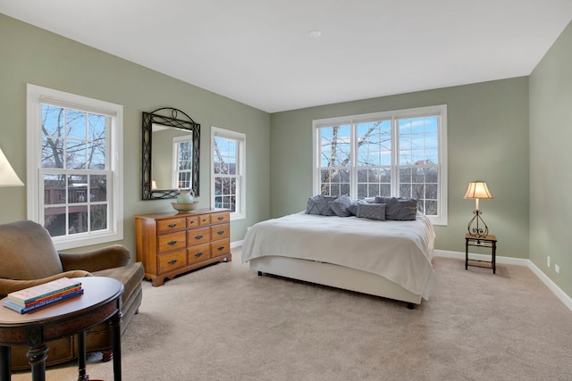 bedroom featuring light carpet, multiple windows, and baseboards