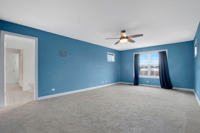 carpeted empty room with a ceiling fan and baseboards